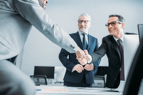 Compliance professionals shaking hands in a conference room. 