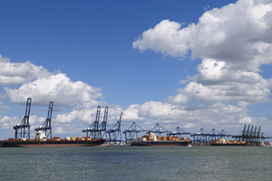 Three large shipping freighters docked and offloading goods in the UK. 