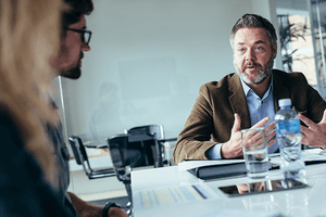 Colleagues conversing at meeting table 